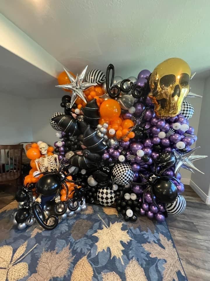 A bold Halloween balloon wall packed with skeletons, spiders, bats, and a standout skull.