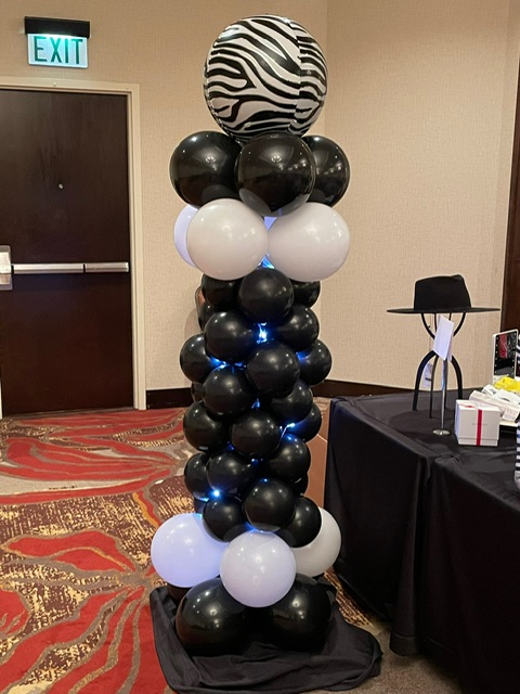 Black‑and‑white zebra column topped with a zebra orbz and wrapped in soft fairy lights.